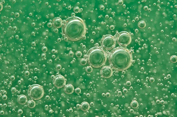 Burbujas de oxígeno macro en el agua sobre un fondo verde — Foto de Stock