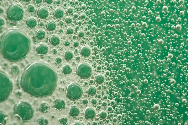 Burbujas de oxígeno macro en el agua sobre un fondo verde — Foto de Stock