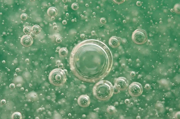 Bulles d'oxygène macro dans l'eau sur un fond vert — Photo