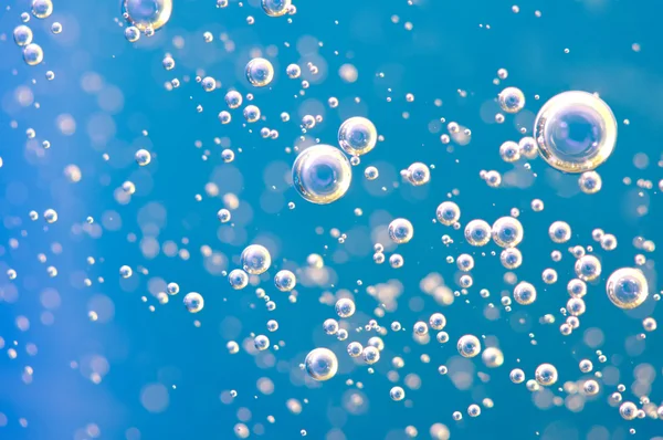 Macro zuurstofbellen in water op blauwe achtergrond — Stockfoto