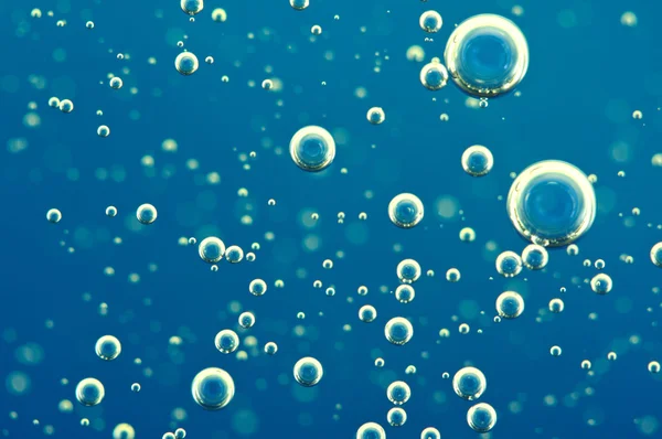 Macro Oxygen bubbles in water on blue background — Stock Photo, Image