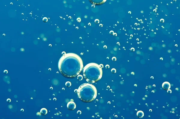 Macro Oxygen bubbles in water on blue background — Stock Photo, Image