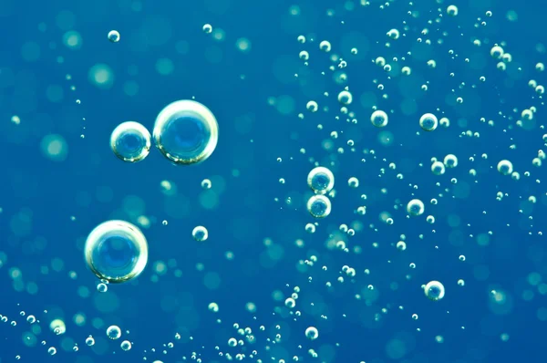 Macro zuurstofbellen in water op blauwe achtergrond — Stockfoto