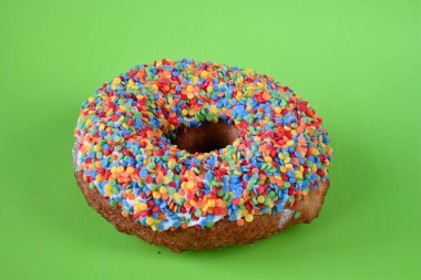 Yeşil arka planda çok renkli bir şekerleme soslu donut..