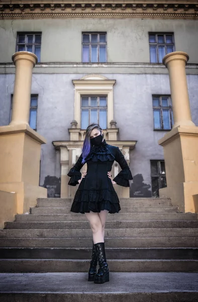 黒の防護マスクと階段のゴシック様式の黒のドレスの女性 — ストック写真