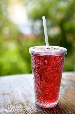 Yeşil bulanık arkaplanda kızılcık suyu ve buz küpleriyle kokteyl..