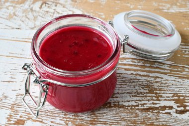 Açık cam bir kavanozdaki kirazlı krema balı tahtadan izole edilmiş..