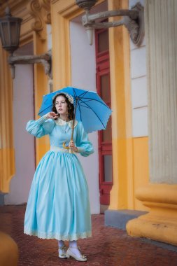 Malikanenin yanında şemsiyesi olan mavi elbiseli genç bir kadın.