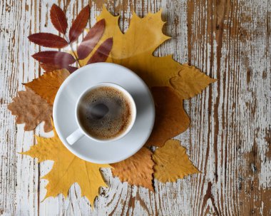 Ahşap masa manzaralı sonbahar yapraklı bir fincan kahve..