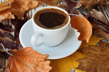 Ahşap masa manzaralı sonbahar yapraklı bir fincan kahve..