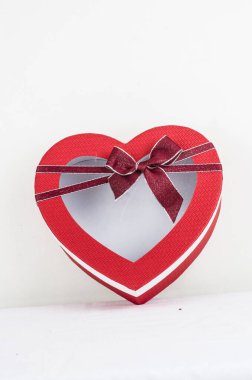 Beyaz arka planda kırmızı kurdeleli kalp kutusu. 