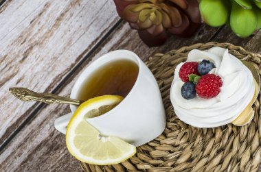 Ahşap bir arka planda çilekli çay ve pasta..