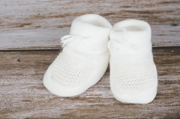 Tahta arka planda yeni doğmuş bebek ayakkabıları