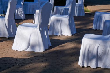 Sosyal uzaklık için hazırlanmış geniş bir grup boş beyaz sandalye açık hava iş konferansına konuk ağırlamaya hazır. COVID-19 salgın sırasında sağlık ve güvenlik tedbirleri insanlar arasında mesafe gerektirir