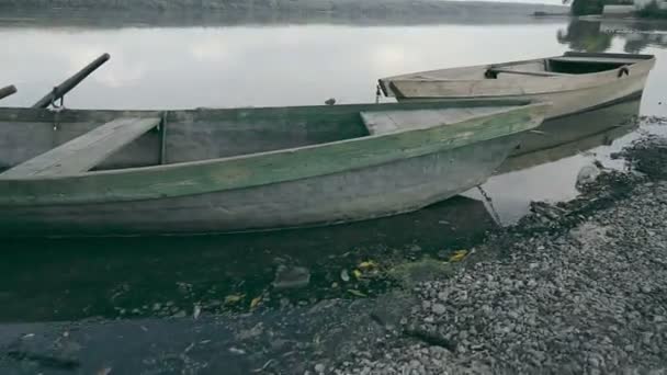 Viejos botes de madera en la orilla del río. Dos viejos barcos pesqueros de madera cerca de la orilla del río. Paisaje fluvial en verano con dos barcos de madera cerca de la orilla del río. — Vídeos de Stock