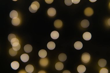 Yılbaşı çelenklerinin arka planı yıldızlar gibi. Noel atmosferinde çelenkler yankılanıyor.