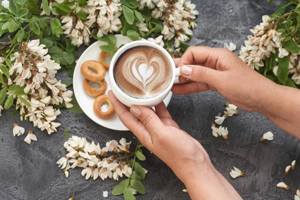 Spring layout with Coffee in female hands and white acacia flowers.