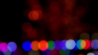 Siyah arka planda çok renkli bokeh ışıkları parıldıyor. Yeni yıl arkaplanı. Soyut bulanık Noel şenlik videosu.