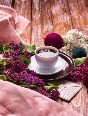 Kahve fincanı ve bahçe masasında renkli leylak çiçekleri.