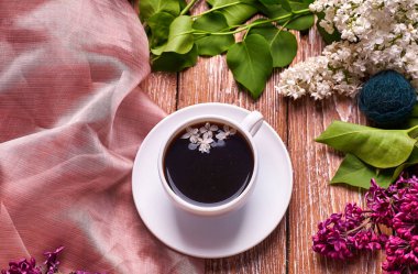 Kahve fincanı ve bahçe masasında renkli leylak çiçekleri.