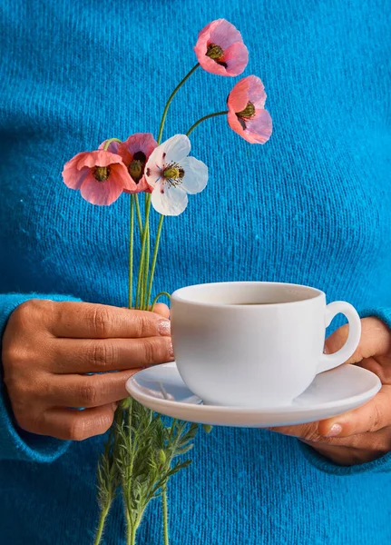 ポピーの花を持った女の子と暖かい朝のコーヒーの白いカップ 青の背景 — ストック写真