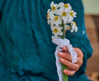 Elinde beyaz nergis buketi tutan bir kadın.
