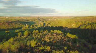 Sonbaharda bir tarlanın ve ormanın üzerinde uçmak. Sarı ağaçlar güneş tarafından aydınlatılıyor. Havadan yukarıdan aşağıya doğru. Sonbaharda karışık orman. Ormanın kenarındaki sarı ağaçlar, tarla sınırındaki.