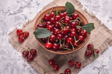 Gri arka planda kırmızı kirazlı kase, üst görünüm