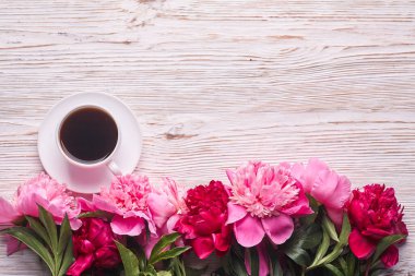 Pembe şakayıklar ve gri ahşap arka planda bir fincan kahve. Uzayı kopyala, üst görünüm. Anneler Günü, Sevgililer Günü, Doğum günü konsepti.