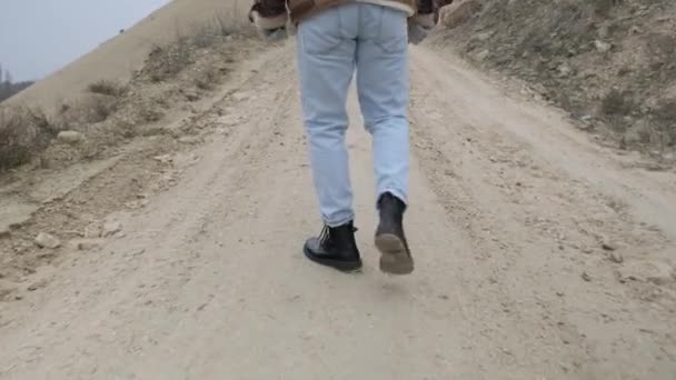 Un joven con chaqueta y jeans camina por un carier de piedra abandonado — Vídeos de Stock