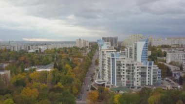Şehir binalarının manzarası olan büyük bir sonbahar ormanı üzerinde havadan uçuş. Kishinev, Moldova.