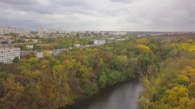 Şehir binalarının manzarası olan büyük bir sonbahar ormanı üzerinde havadan uçuş. Kishinev, Moldova.