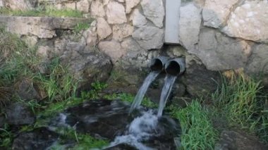 Temiz, şeffaf bir dağ suyu akıntısı. Metal oluklardan aşağı akıyor. Yakından görülüyor.