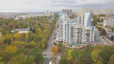 Şehir binalarının manzarası olan büyük bir sonbahar ormanı üzerinde havadan uçuş. Kishinev, Moldova.