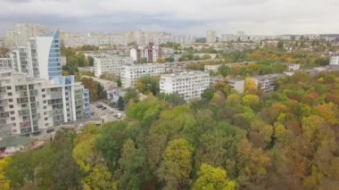 Şehir binalarının manzarası olan büyük bir sonbahar ormanı üzerinde havadan uçuş. Kishinev, Moldova.