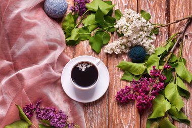 Kahve fincanı ve bahçe masasında renkli leylak çiçekleri.