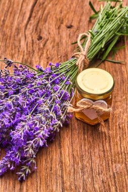 Lavanta yağı, tahta üzerinde bir demet lavanta çiçeği.