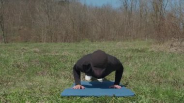 Oyuncu sporcu, parkta spor minderinde bacağını uzatıyor.