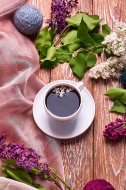 Kahve fincanı ve bahçe masasında renkli leylak çiçekleri.