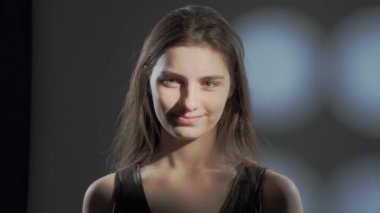 Stüdyoda sakince kameraya bakan kahverengi saçlı genç kızın portresini kapat..