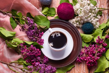 Kahve fincanı ve bahçe masasında renkli leylak çiçekleri.