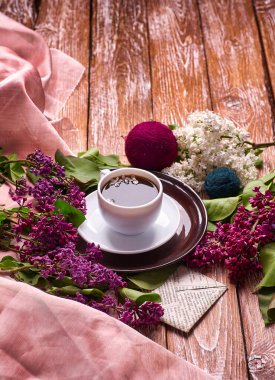 Kahve fincanı ve bahçe masasında renkli leylak çiçekleri.