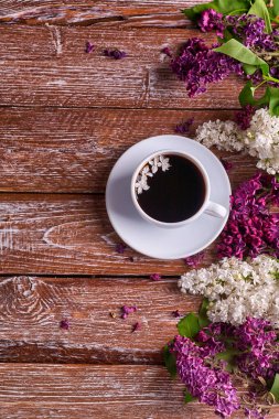 Kahve fincanı ve bahçe masasında renkli leylak çiçekleri.