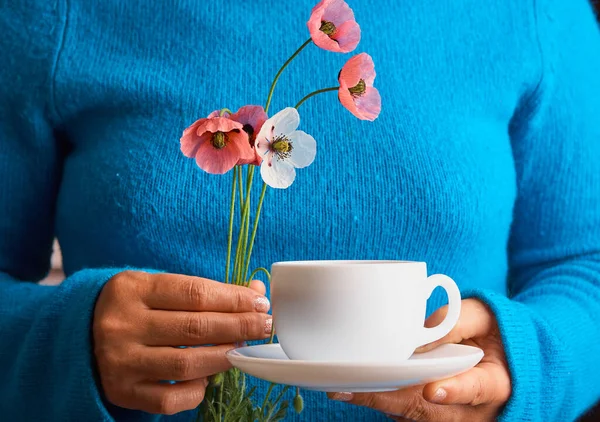 ポピーの花を持った女の子と暖かい朝のコーヒーの白いカップ 青の背景 — ストック写真