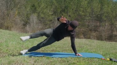 Oyuncu sporcu, parkta spor minderinde bacağını uzatıyor.