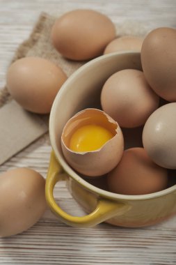 Ahşap zeminde bir kase çiğ tavuk yumurtası.