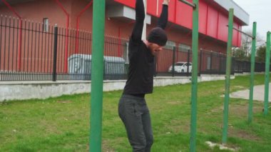 Spor giyim sektöründe genç bir adam şehrin spor sahasındaki yatay bir barda kendini yukarı çekiyor..