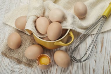 Ahşap zeminde bir kase çiğ tavuk yumurtası.