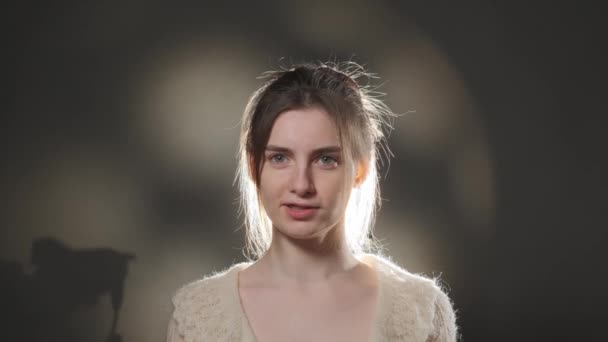 Close up retrato de jovem com cabelo castanho assistindo calmamente em câmera em estúdio. — Vídeo de Stock