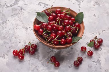 Gri arka planda kırmızı kirazlı kase, üst görünüm